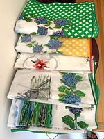 Stack of five folded printed cotton tablecloths showing edges and patterns