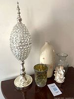 Group shot showing crystal pedestal finial, cream ceramic vase, mosaic votive, clear glass vase and porcelain cherub figurine