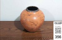 Front view of terracotta orange ribbed ceramic vase on wooden surface