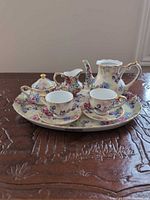 Full view of all eight miniature tea service pieces on tray