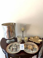 Full lot overview showing vase, crystal holders, gold bowl, two winter plates