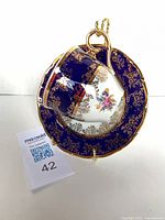 Cup resting on saucer showing cobalt blue glaze, gold gilt, floral design