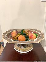 Compote on pedestal table filled with stone and glass fruit