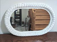 Front view of oval white wicker mirror