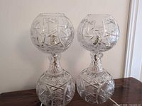 Front view of both cut crystal pinwheel table lamps on wood surface