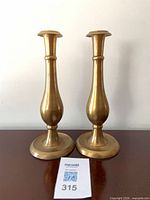 front view of both brass candlesticks standing side by side