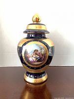 Front view showing hand-painted scene, gilded borders and cobalt blue glaze