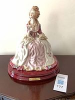 Full view of figurine on wooden base with auction tag visible