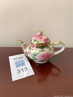 Front view of porcelain floral teapot trinket box showing rose pattern and gold trim
