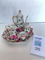 Whole miniature tea set arranged on octagonal plate showing pattern and gold trim
