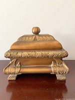 Front view of closed ornate gold-bronze jewelry box