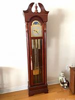 Full front view of Ridgeway grandfather clock showing dial, case, pendulum and weights