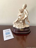 Front view of Giuseppe Armani porcelain figurine with display base and lot tag visible
