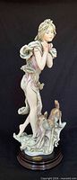 Front view of porcelain figurine showing woman with deer on wood base