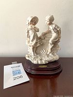 Front view of figurine on base, boy offering gift to girl