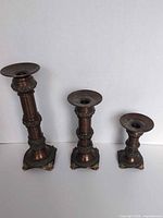 Front view of three bronze/copper tone candle holders