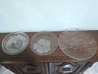 Three pressed glass plates on cabinet top