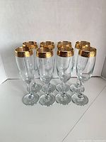 Eight champagne flutes grouped to show overall condition and matching gold rims