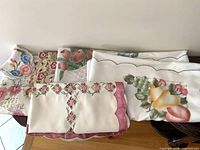 Stack of folded floral table linens showing various patterns and scalloped edges