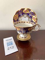 Teacup set inside saucer on stand showing cobalt blue, gold gilt, floral pattern