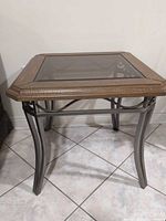 Full view of end table showing glass top, wood frame, metal legs