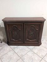 Front view of dark brown wood veneer console cabinet showing two ornate doors