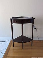 Front view of dark cherry triangular corner end table showing drawer and lower shelf