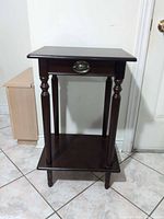 Full view of the cherry finish end table showing drawer, turned legs and lower shelf