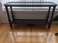 Front view of dark wood console table with glass top and lower shelf