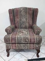 Front view of wingback armchair showing overall design, upholstery pattern and cabriole legs