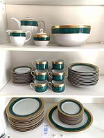 Teapot, creamer, covered sugar, serving bowl and teacup on upper shelf