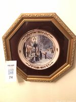 Front view of octagonal gold frame housing round plate with burgundy mat