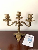 Front view of ornate brass three-arm candelabra