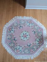 Full view of pink octagonal floral rug showing design and fringe