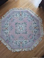 Full view of octagonal pink floral rug showing shape, pattern and fringe