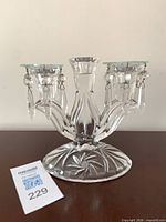 Front view of clear glass three-arm candelabra showing prisms and pinwheel base