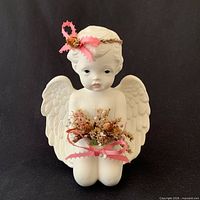 Front view of kneeling porcelain angel with bouquet and ribbon