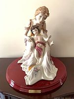 Front view of Capodimonte mother and child porcelain figurine on red wood base