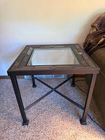 Square end table front view showing metal frame, glass top, tile border