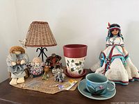 Overview of all items on tabletop including dolls, lamp, pot, cup & saucer, figurines, jewelry findings