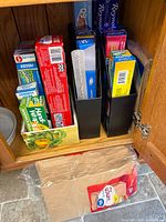 Cabinet view showing multiple boxes of foil, plastic bags, lunch bags