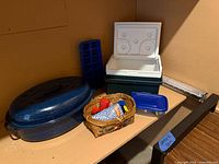 All items grouped: graniteware roaster, Coleman cooler, wicker basket with utensils, ice cube tray, food storage container