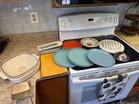 Overview of casserole dish, cutting board, grater, plates, rack on stovetop