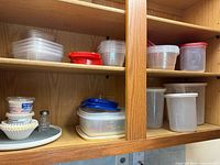 Cabinet shelves holding stacks of plastic containers with red and clear lids