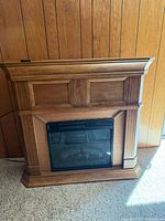 Front view of medium brown oak-tone electric fireplace mantel with insert