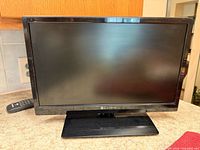 Front view of Element ELEFW195 television on stand with remote