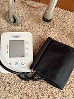 Equate digital blood pressure monitor with cuff on carpet next to walker leg
