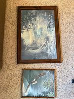 Both framed prints laid on carpet, showing size difference and brown wood frames