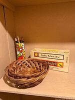Wicker baskets, floral tin with tools and electric knife box on shelf