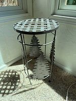 Full view of metal plant stand showing lattice top and tree cutout sides